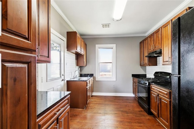 316 Milling Ave, Luling, LA 70070 - kitchen featuring black appliances, under cabinet range hood, decorative backsplash, a sink, and dark wood-style floors