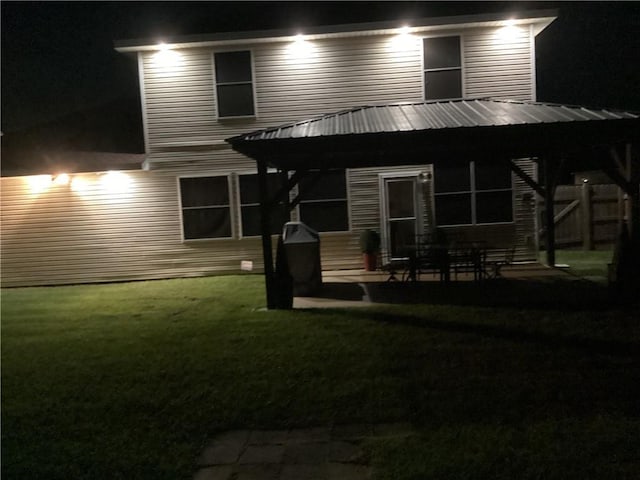 2132 Wellington Ln, Slidell, LA 70461 - back of house at twilight featuring a patio and a lawn