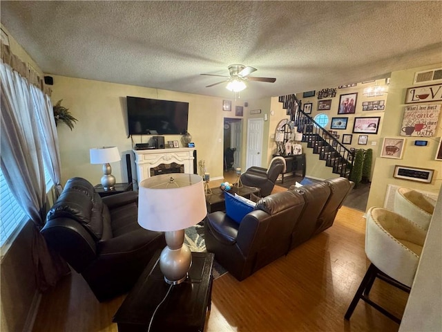 2132 Wellington Ln, Slidell, LA 70461 - living area with wood finished floors, ceiling fan, a textured ceiling, a fireplace, and stairway