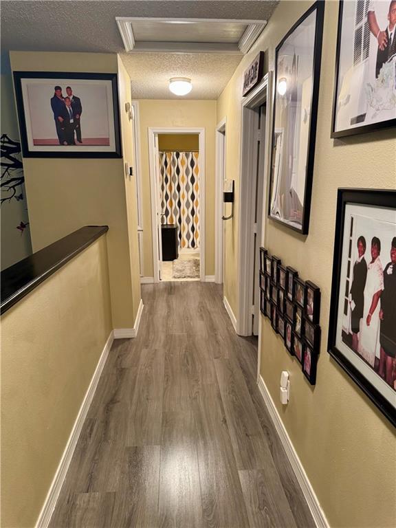 2132 Wellington Ln, Slidell, LA 70461 - corridor with dark wood-style floors, a textured ceiling, attic access, and baseboards