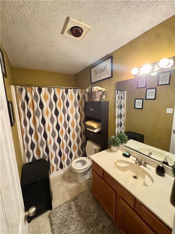 2132 Wellington Ln, Slidell, LA 70461 - full bathroom with a textured ceiling, vanity, toilet, tile patterned floors, and a shower with shower curtain