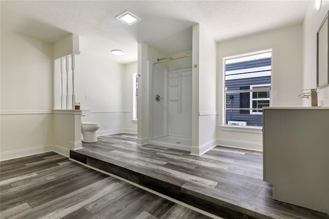 60078 W Park Cir, Lacombe, LA 70445 - full bathroom with wood finished floors, a stall shower, toilet, baseboards, and a textured ceiling