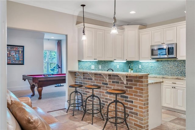 11 Arbor Cir, New Orleans, LA 70131 - kitchen with stainless steel microwave, light stone countertops, a kitchen bar, pool table, and pendant lighting