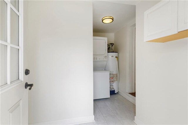 912 Spain St, New Orleans, LA 70117 - washroom with stacked washer / drying machine, gas water heater, light marble finish flooring, and baseboards