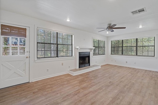 718 E 10th Ave, Covington, LA 70433 - unfurnished living room featuring light wood finished floors, a ceiling fan, a fireplace with raised hearth, baseboards, and recessed lighting