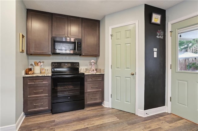 kitchen with stainless steel microwave, black / electric stove, dark brown cabinets, wood finished floors, and baseboards