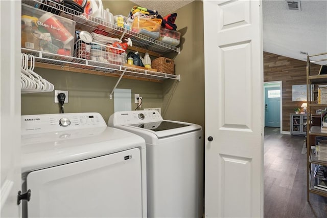 laundry room featuring independent washer and dryer, wooden walls, wood finished floors, and a textured ceiling
