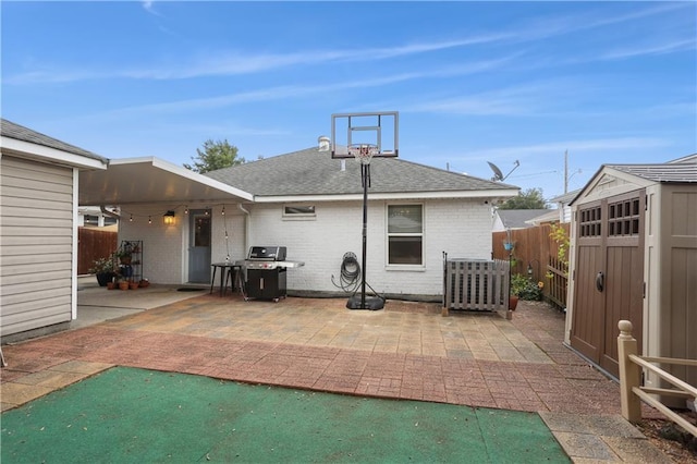 rear view of house with a patio, fence, an outdoor structure, a storage unit, and brick siding