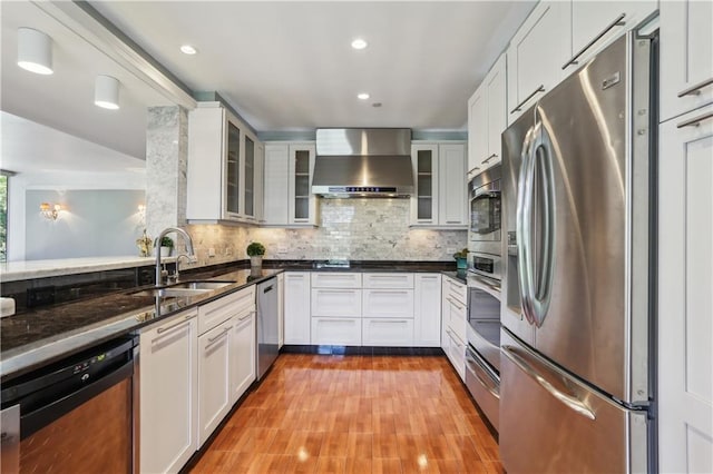 2100 Saint Charles Ave Unit 4D, New Orleans, LA 70130 - kitchen featuring stainless steel appliances, wall chimney range hood, a sink, dark stone countertops, and decorative backsplash