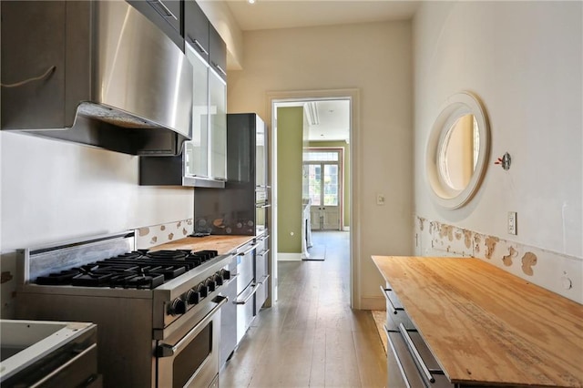 538 Governor Nicholls St, New Orleans, LA 70116 - kitchen with butcher block countertops, high end range, exhaust hood, light wood-style floors, and baseboards