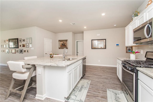 3663 Trestle Crossing Ave, Slidell, LA 70461 - kitchen with appliances with stainless steel finishes, a sink, baseboards, a kitchen island with sink, and white cabinetry