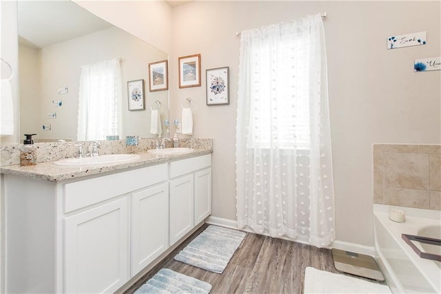 3663 Trestle Crossing Ave, Slidell, LA 70461 - bathroom with a garden tub, wood finished floors, double vanity, and baseboards