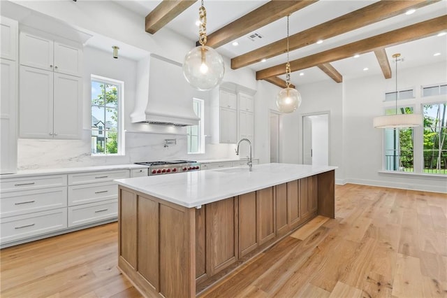 136 Linnette Ln, Mandeville, LA 70471 - kitchen with premium range hood, backsplash, a spacious island, a sink, and light wood-type flooring
