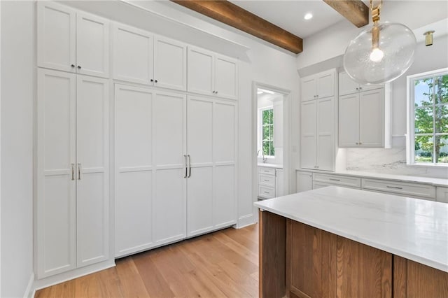 136 Linnette Ln, Mandeville, LA 70471 - kitchen featuring light wood-style flooring, beam ceiling, white cabinets, decorative backsplash, and light stone counters