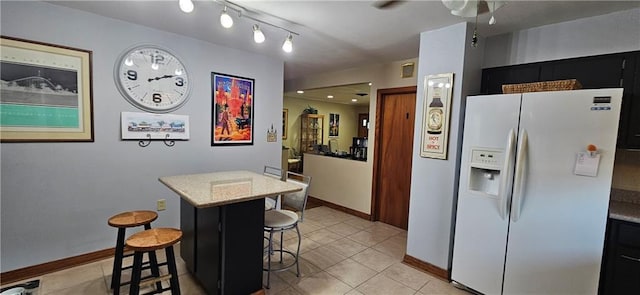 3231 47th St, Metairie, LA 70001 - kitchen with white fridge with ice dispenser, a breakfast bar area, light tile patterned floors, a ceiling fan, and baseboards