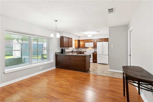 2701 Chenier St, Marrero, LA 70072 - kitchen with white appliances, a peninsula, light wood-style flooring, a sink, and hanging light fixtures