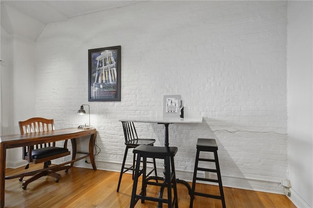 760 Magazine St Unit 113, New Orleans, LA 70130 - dining area featuring wood finished floors, brick wall, and baseboards