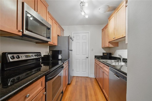 760 Magazine St Unit 113, New Orleans, LA 70130 - kitchen featuring appliances with stainless steel finishes, a sink, light wood-style floors, and dark stone counters