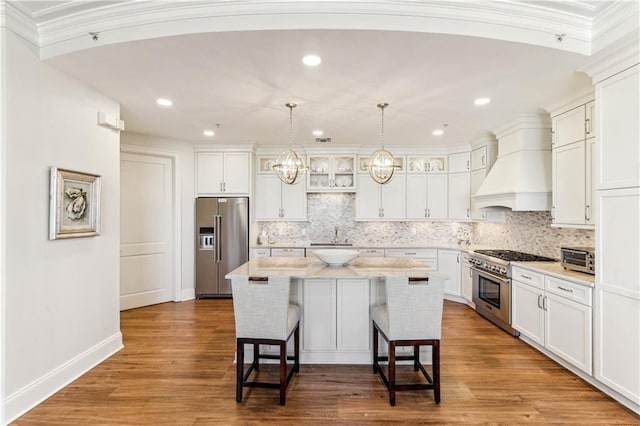 232 Lake Marina Ave Unit 10-D, New Orleans, LA 70124 - kitchen featuring premium range hood, stainless steel appliances, white cabinetry, a breakfast bar area, and recessed lighting
