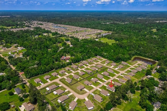 aerial view of property's location featuring a heavily wooded area, a nearby body of water, and nearby suburban area