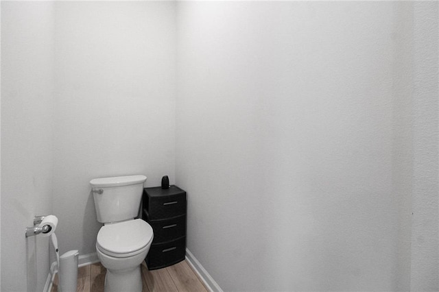 bathroom featuring toilet, wood finished floors, and baseboards