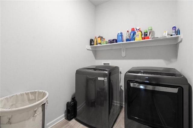 washroom featuring washing machine and clothes dryer, light wood-style flooring, and baseboards