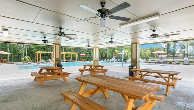 view of patio featuring fence, ceiling fan, and a community pool