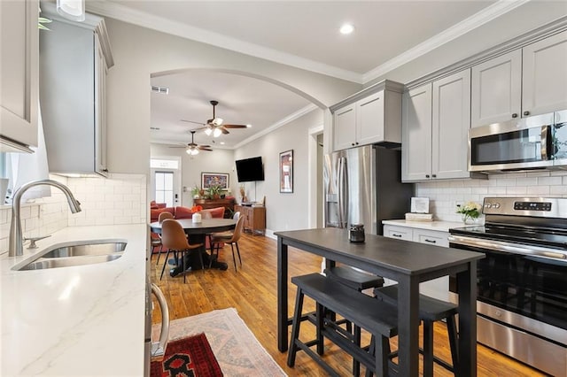 722 Luling Ave, Luling, LA 70070 - kitchen featuring appliances with stainless steel finishes, a sink, arched walkways, a ceiling fan, and ornamental molding