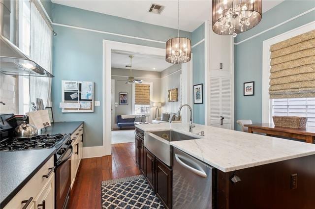 3451 Constance St, New Orleans, LA 70115 - kitchen with gas stove, wall chimney exhaust hood, a chandelier, stainless steel dishwasher, and a sink