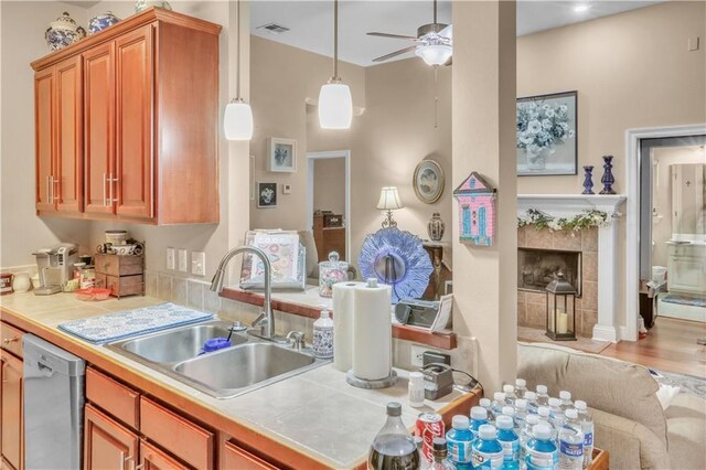 270 Libra Ave Unit B, Mandeville, LA 70471 - kitchen with dishwasher, a sink, ceiling fan, brown cabinets, and a tile fireplace