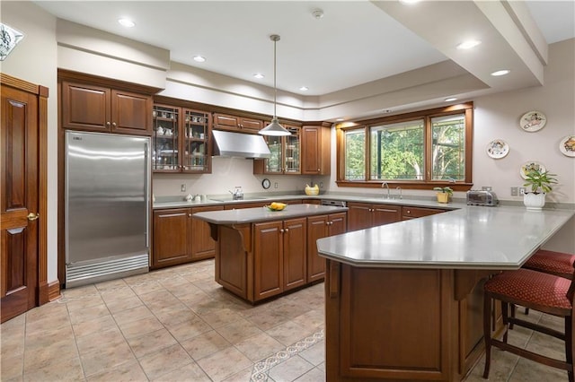 22450 Elderberry Ln, Bush, LA 70431 - kitchen featuring built in fridge, under cabinet range hood, a kitchen breakfast bar, a peninsula, and glass insert cabinets