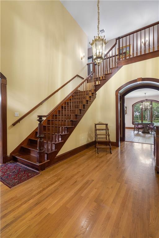 22450 Elderberry Ln, Bush, LA 70431 - stairway featuring a chandelier, a high ceiling, wood finished floors, arched walkways, and baseboards