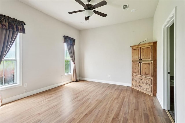 unfurnished bedroom with light wood-type flooring, multiple windows, baseboards, and ceiling fan