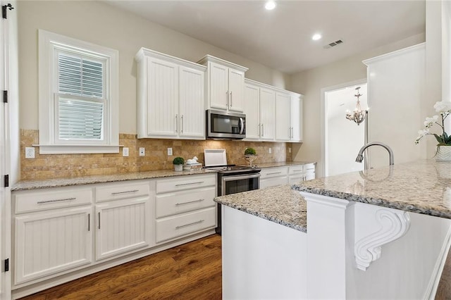 993 Beauregard Pkwy, Covington, LA 70433 - kitchen featuring appliances with stainless steel finishes, white cabinetry, tasteful backsplash, light stone countertops, and recessed lighting