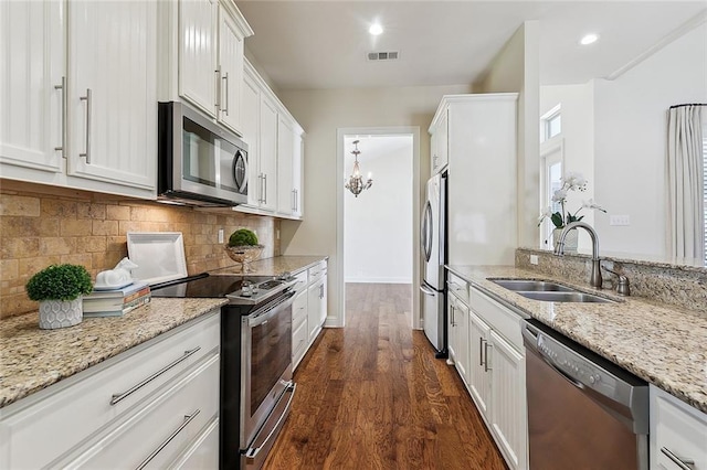 993 Beauregard Pkwy, Covington, LA 70433 - kitchen featuring stainless steel appliances, a sink, white cabinets, dark wood-style flooring, and decorative backsplash