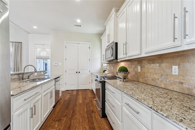 993 Beauregard Pkwy, Covington, LA 70433 - kitchen featuring appliances with stainless steel finishes, a sink, white cabinets, dark wood-style flooring, and backsplash