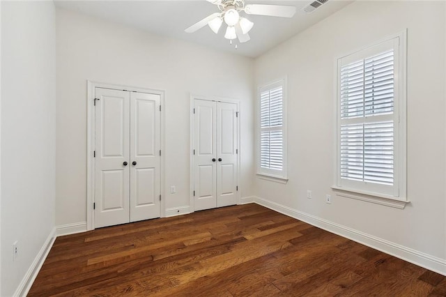 993 Beauregard Pkwy, Covington, LA 70433 - unfurnished bedroom with multiple closets, dark wood-style flooring, baseboards, and a ceiling fan