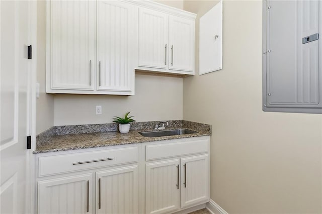 993 Beauregard Pkwy, Covington, LA 70433 - kitchen featuring a sink, white cabinetry, electric panel, and dark stone countertops