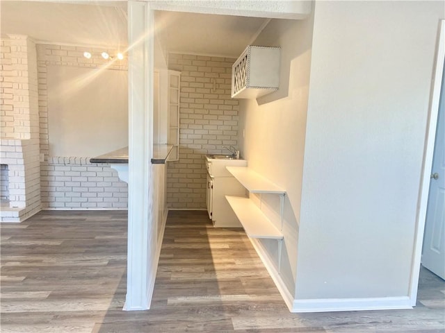 7511 Fieldston Rd, New Orleans, LA 70126 - bathroom with wood finished floors, brick wall, and a sink