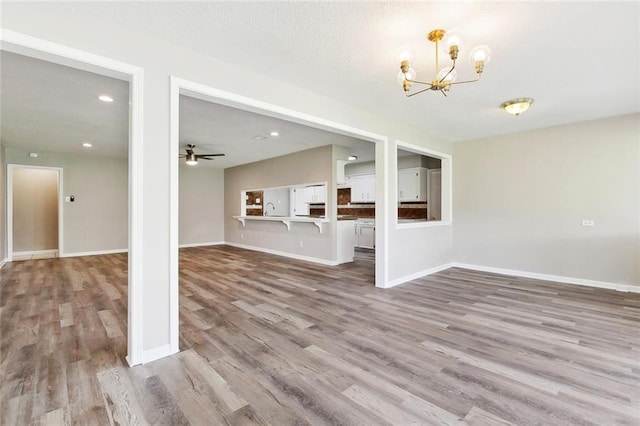 7511 Fieldston Rd, New Orleans, LA 70126 - unfurnished living room with wood finished floors, a chandelier, baseboards, recessed lighting, and a ceiling fan