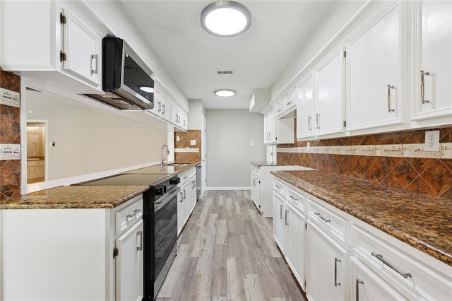 7511 Fieldston Rd, New Orleans, LA 70126 - kitchen featuring black / electric stove, a sink, stainless steel microwave, white cabinets, and dark stone countertops