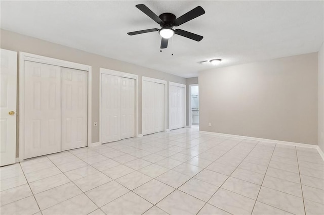 7511 Fieldston Rd, New Orleans, LA 70126 - unfurnished bedroom with two closets, baseboards, light tile patterned flooring, and a ceiling fan