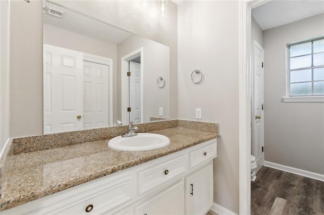 7511 Fieldston Rd, New Orleans, LA 70126 - bathroom with vanity, toilet, wood finished floors, and baseboards