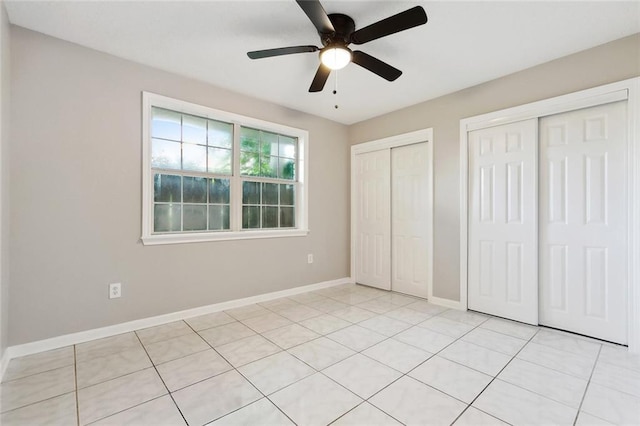7511 Fieldston Rd, New Orleans, LA 70126 - unfurnished bedroom featuring two closets, baseboards, a ceiling fan, and light tile patterned floors