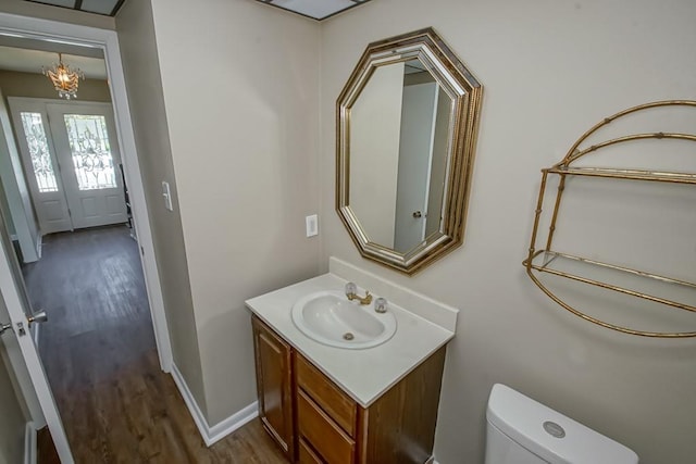 5831 Durbridge Dr, New Orleans, LA 70131 - half bathroom featuring wood finished floors, toilet, vanity, a chandelier, and baseboards