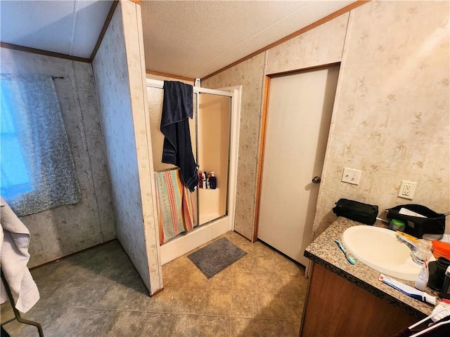 201 Caroline Ave, Port Sulphur, LA 70083 - full bathroom with vaulted ceiling, a shower stall, wallpapered walls, vanity, and a textured ceiling