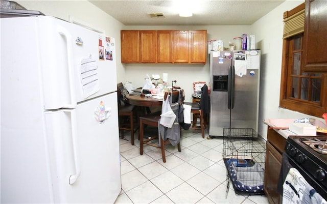 1620 Maplewood Dr, Harvey, LA 70058 - kitchen featuring freestanding refrigerator, stainless steel fridge with ice dispenser, brown cabinets, light tile patterned flooring, and black gas range