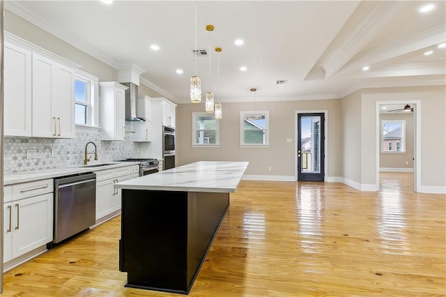 3821 Indiana St, New Orleans, LA 70114 - kitchen featuring appliances with stainless steel finishes, a sink, a center island, wall chimney range hood, and light wood-style flooring