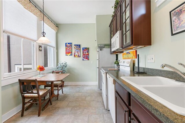 627 Ursulines Ave Unit 9, New Orleans, LA 70116 - kitchen featuring a sink, stove, white microwave, dark countertops, and decorative light fixtures