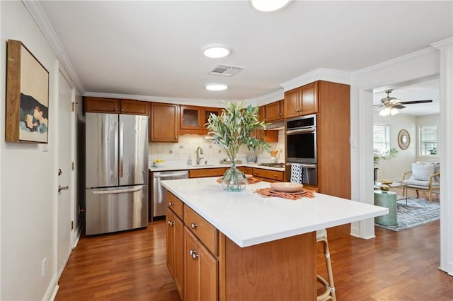 4 Virginia Ct, New Orleans, LA 70124 - kitchen with appliances with stainless steel finishes, brown cabinets, a sink, dark wood-style floors, and decorative backsplash